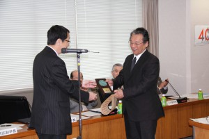 表彰状と記念の楯の授与の様子。 右：山部紀久夫教授（筑波大学数理物質系）